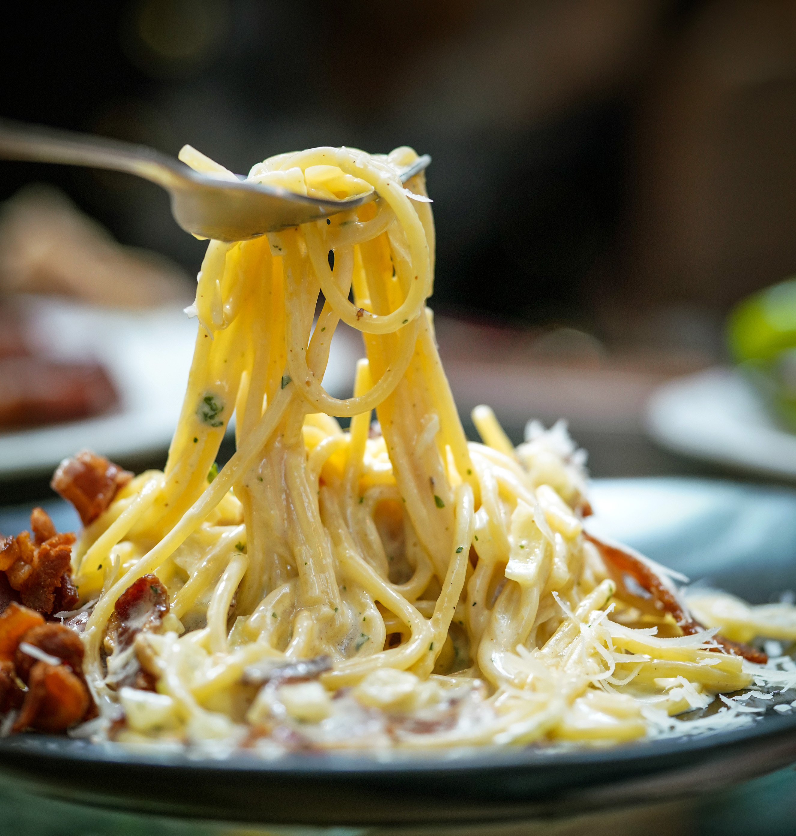 Spaghetti, a delicious pasta Scooping with a fork. Carbonara made with egg, hard cheese, guanciale, bacon and black pepper.